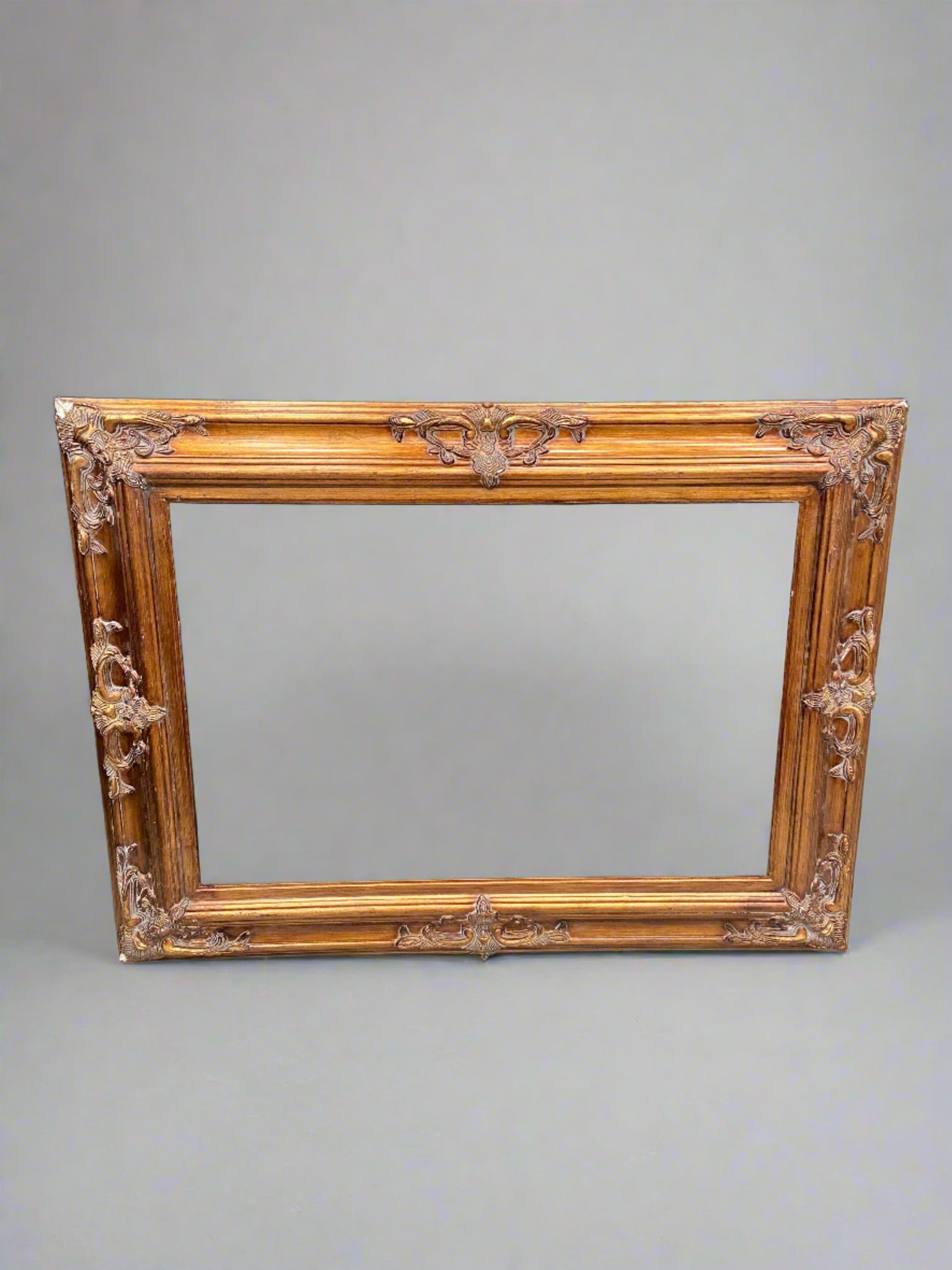 Large rectangular frame painted gold with applied ornate detailing.