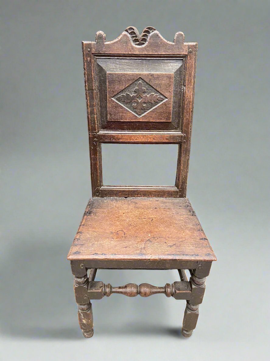 A set of carved panel back chairs with a central kite-shaped medallion, plain seat, and turned legs. It could be as old as the 17th Century.