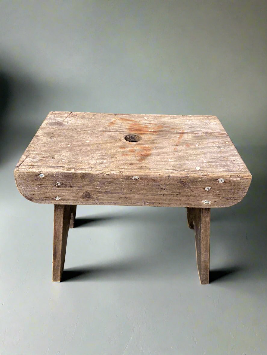 Wooden primitive scratch-built milking stool in an aged condition.