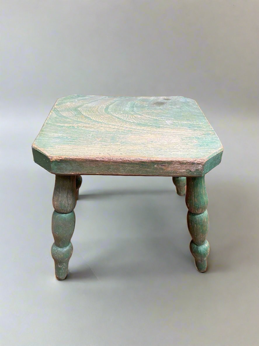 A child's small green stool with turned legs. 