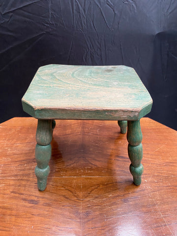 A child's small green stool with turned legs. 