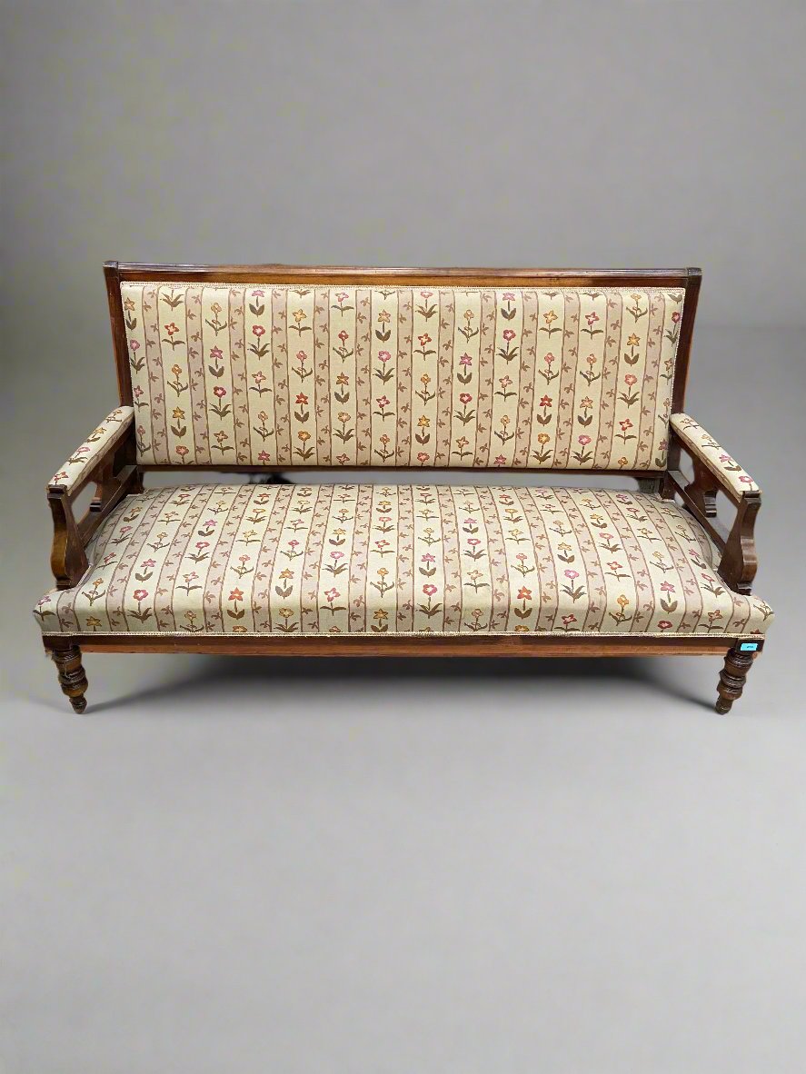 Victorian settee with a dark-turned wooden frame and striped cream floral upholstery. 