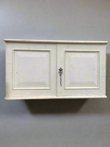 White wall-mounted kitchen cupboard unit, in an aged condition.