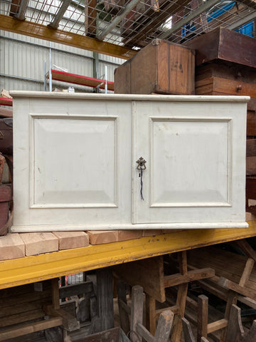 White wall-mounted kitchen cupboard unit, in an aged condition.