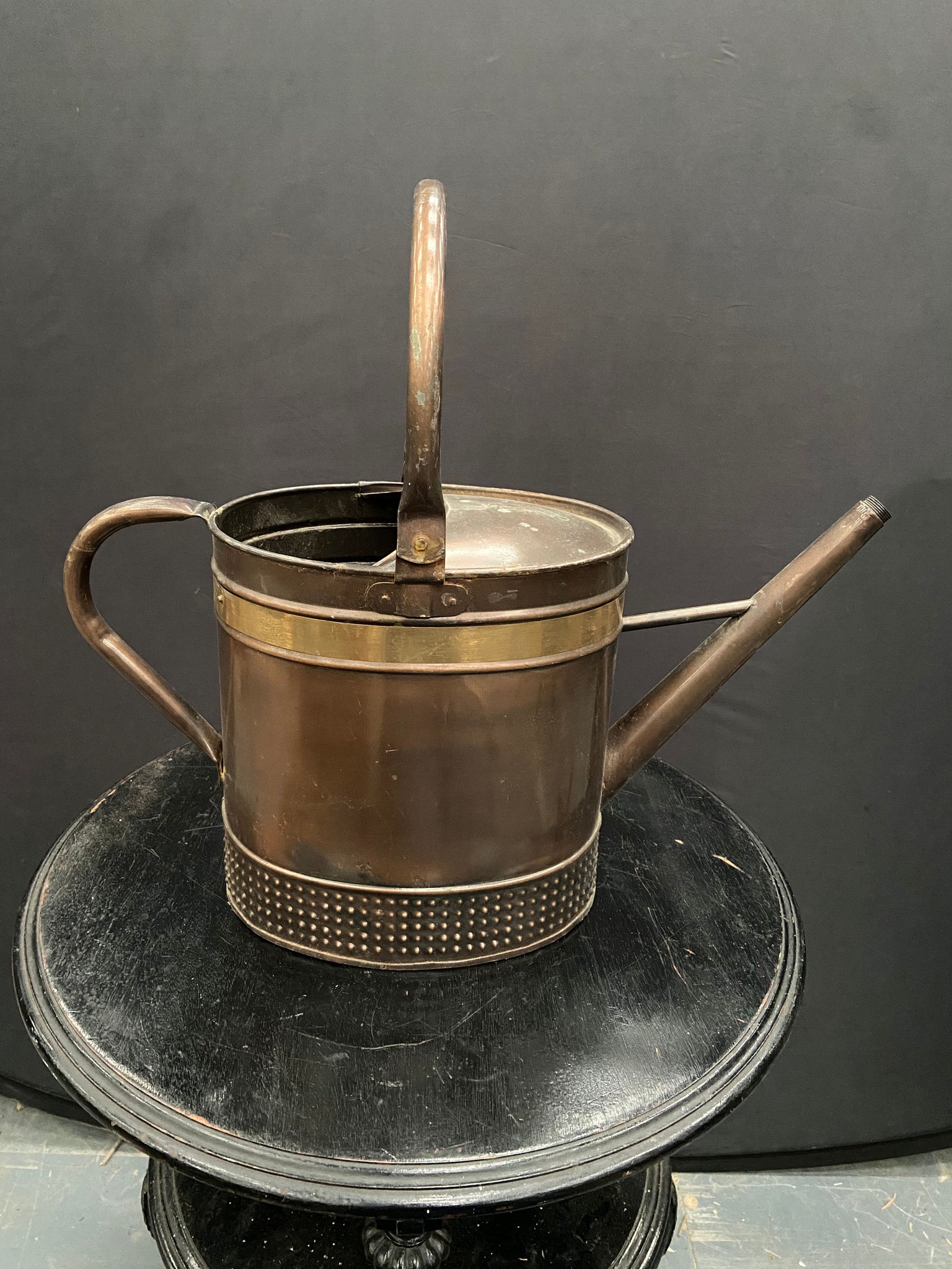 Vintage copper watering can with a decorative brass strip and textured bottom.&nbsp;