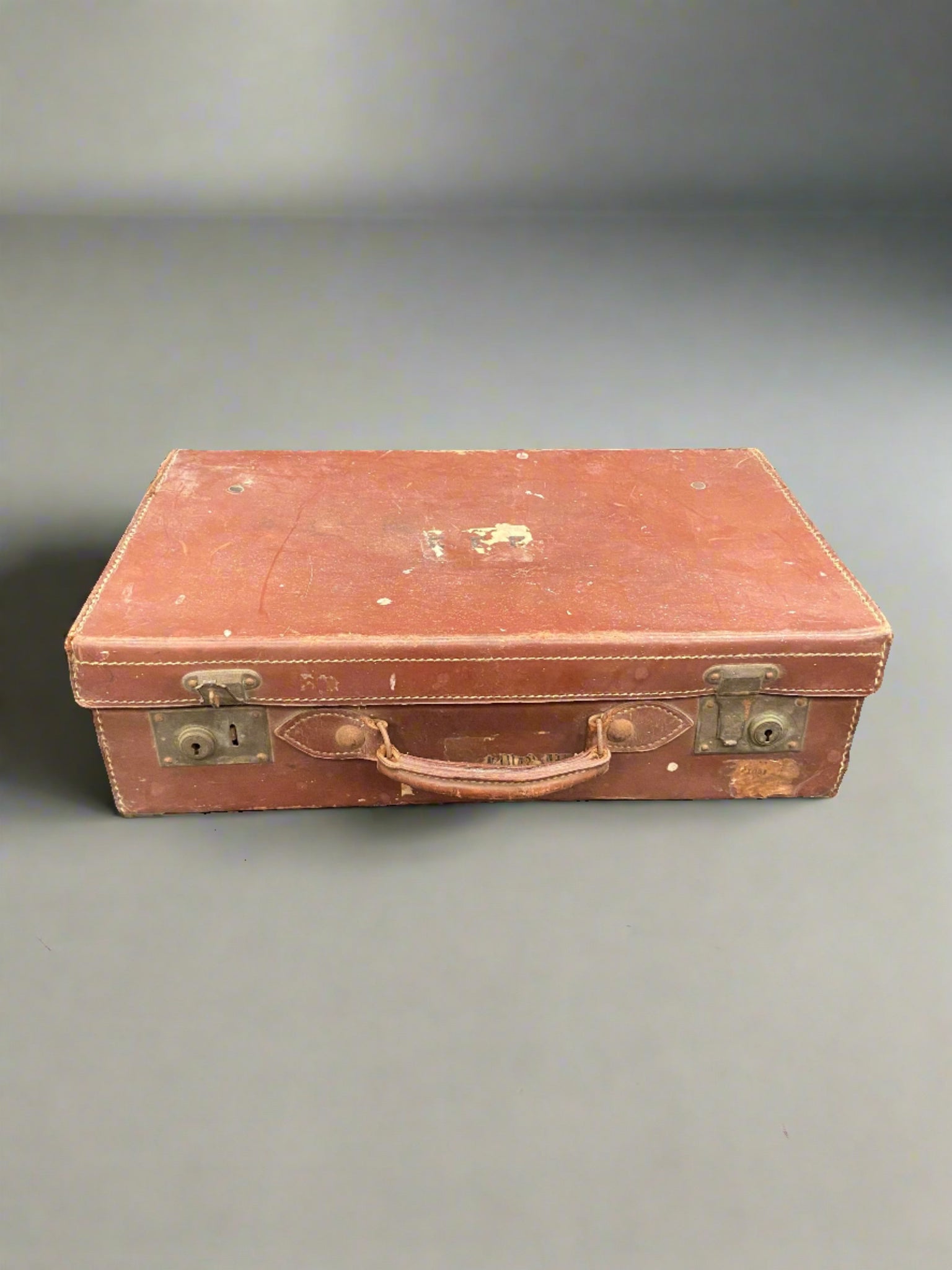 Vintage red-brown leather suitcase with cream stitching.