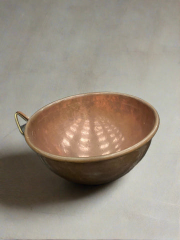 Vintage copper kitchen mixing bowl with a rolled top and single handle.