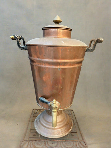 Tall antique copper samovar with black handles and a brass tap.