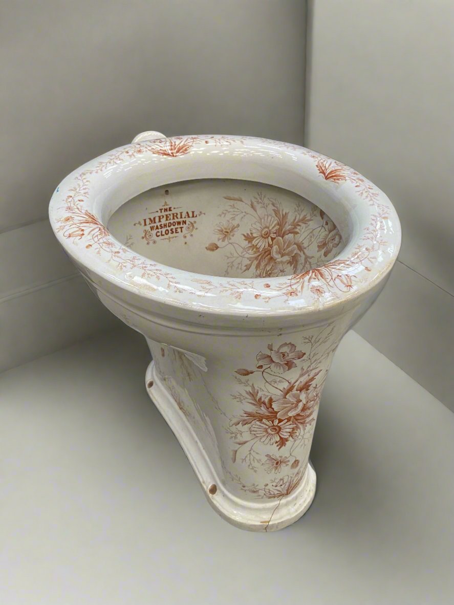 The Imperial washdown closet porcelain toilet, circa the early 20th century. Decorated with burnt orange and white floral patterns.