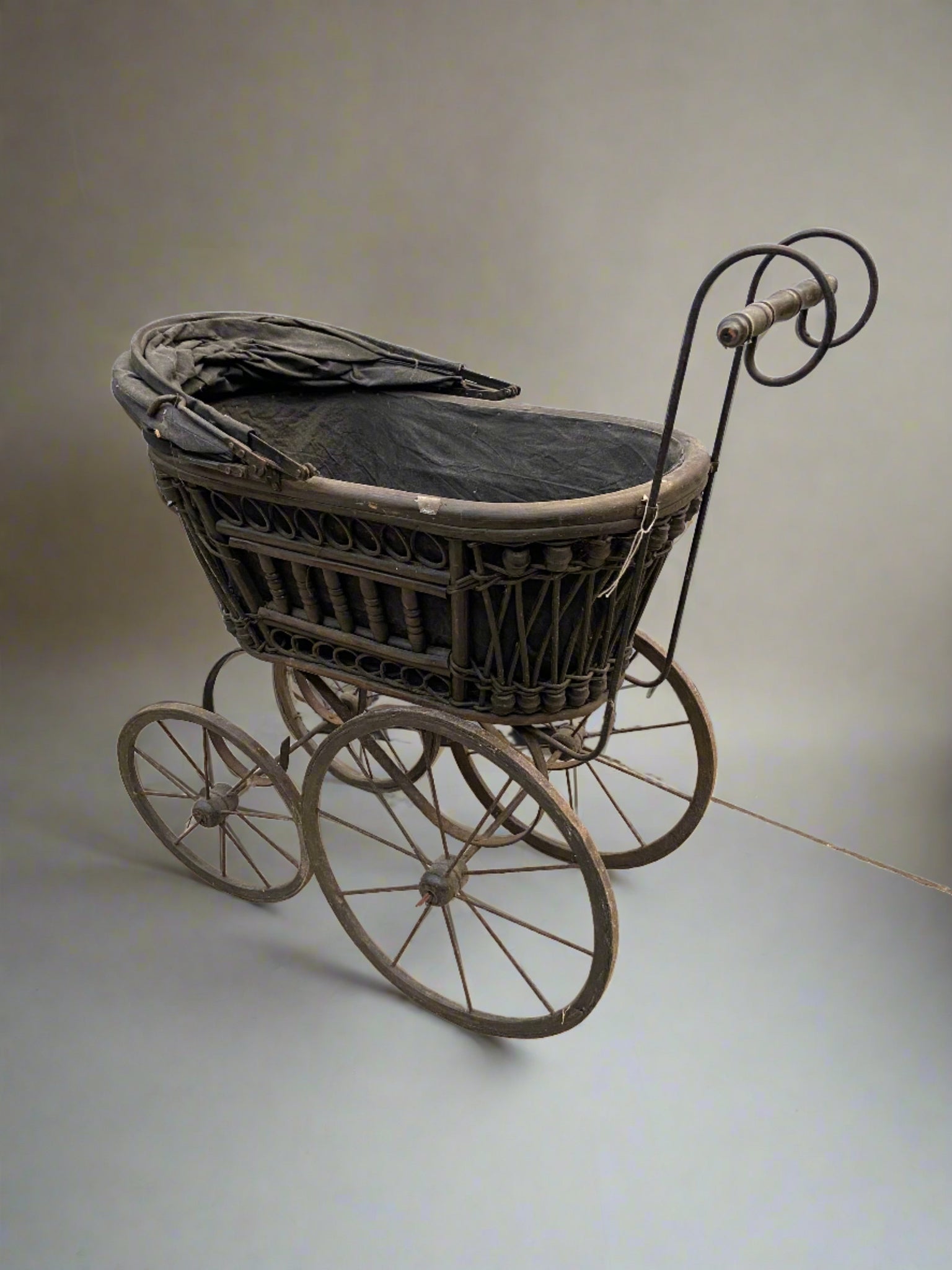 Black Victorian pram with a detailed wooden frame and large curved handles.