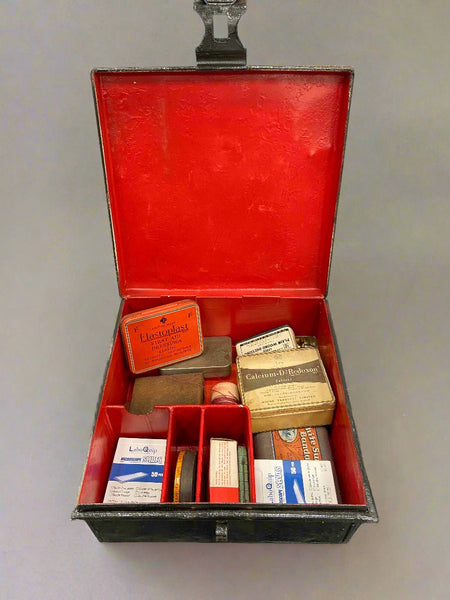 Vintage black metal first aid box, filled with first aid dressings.