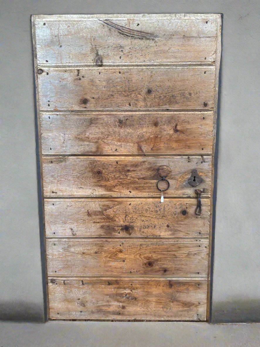 A wide rustic wooden door comprised of seven horizontal panels.