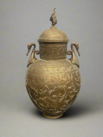 Small ornate brass urn with a Hindu deity head perched on the lid.