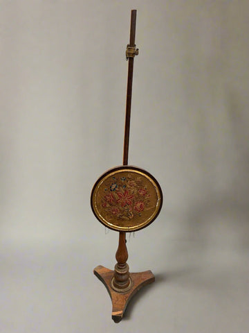 Antique wooden fireside pole screen with a floral embroidered face.