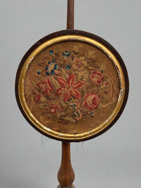 Antique wooden fireside pole screen with a floral embroidered face.