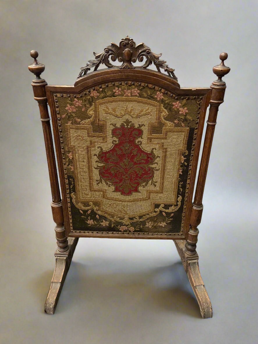 Ornate wooden fireside screen with a delicate tapestry decoration.