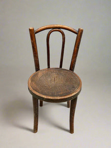 Small round Bentwood chair with a carved pattern in the seat.