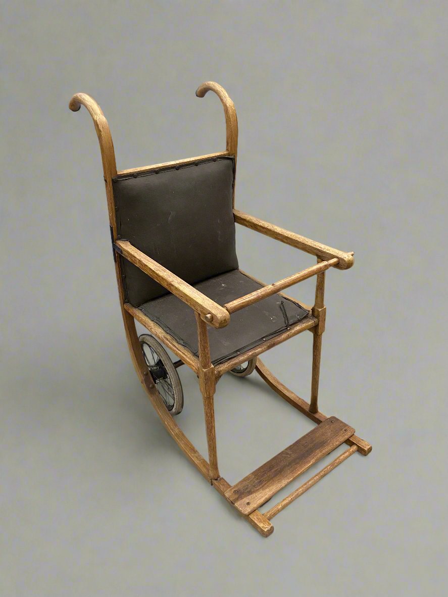 WWI antique wooden wheelchair with brown leather padding, circa 1910s.