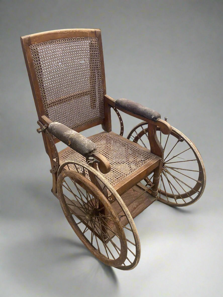 Antique oak and wicker wheelchair in an aged condition.