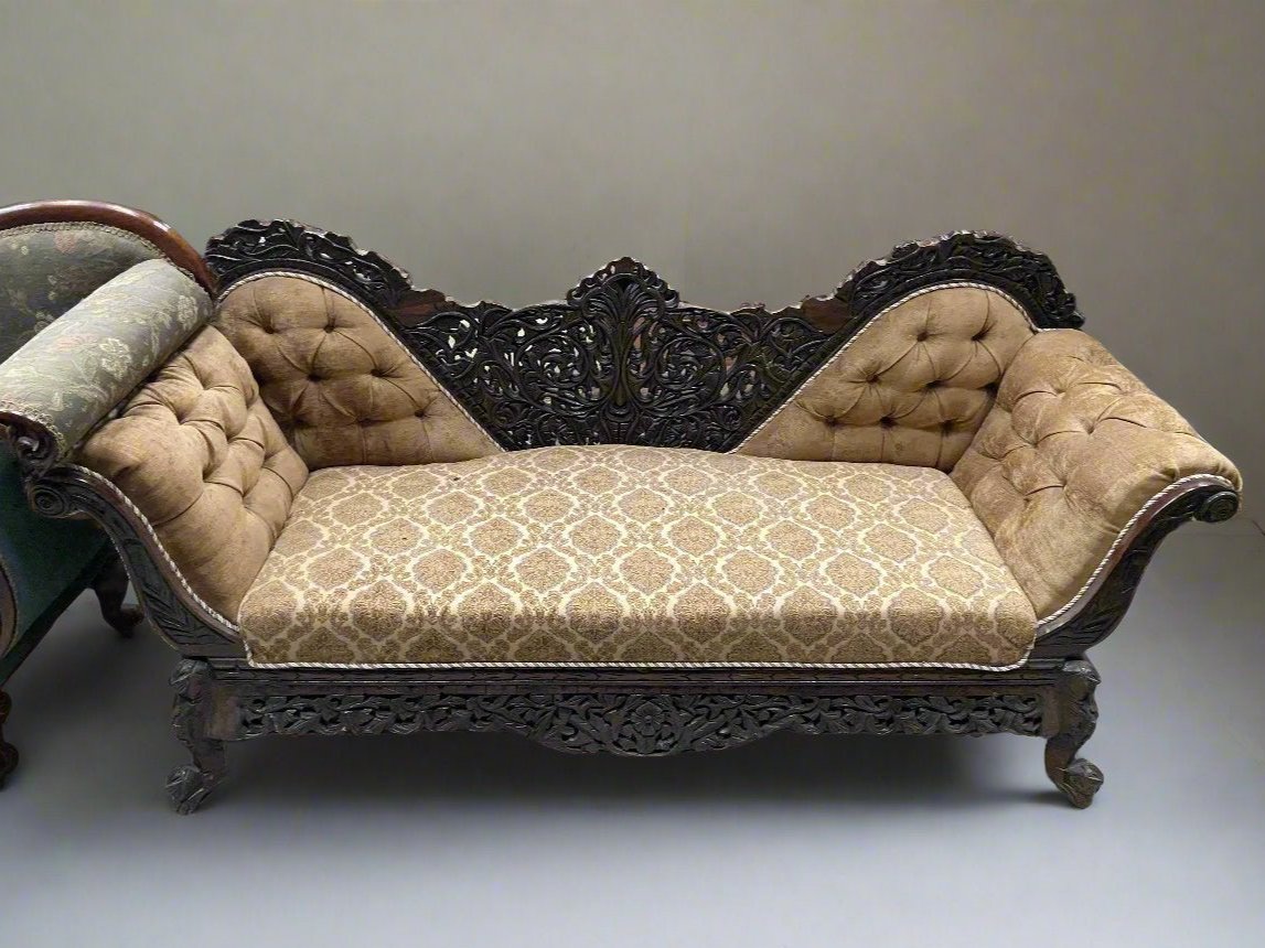 Ornate Indian double armed chaise with an intricate carved frame and golden patterned upholstery.