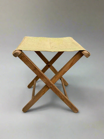 Portable folding camping stool with a beige/green canvas seat.