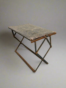 Antique folding metal stool in an aged condition.