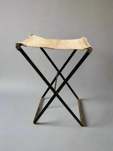 Vintage metal folding stool with a canvas seat.