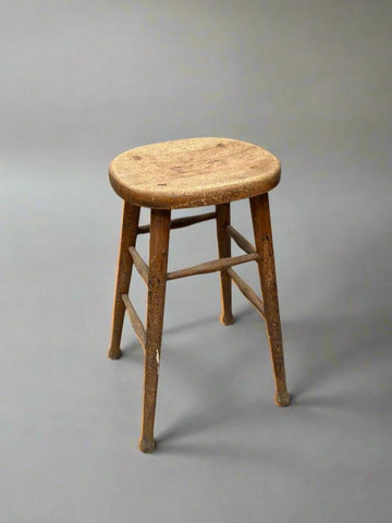 Tall vintage wooden stool with footrests and a circular seat.