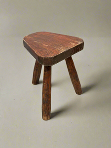 Primitive wooden tripod stool with an unusual shaped seat.