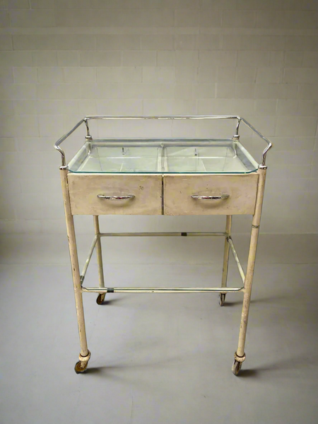 Cream medical trolley with a glass top, on wheels for ease of movement. Ideal hospital ward or dental surgery dressing.