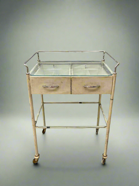 Cream medical trolley with a glass top, on wheels for ease of movement. Ideal hospital ward or dental surgery dressing.