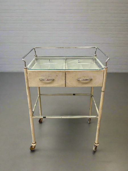 Cream medical trolley with a glass top, on wheels for ease of movement. Ideal hospital ward or dental surgery dressing.