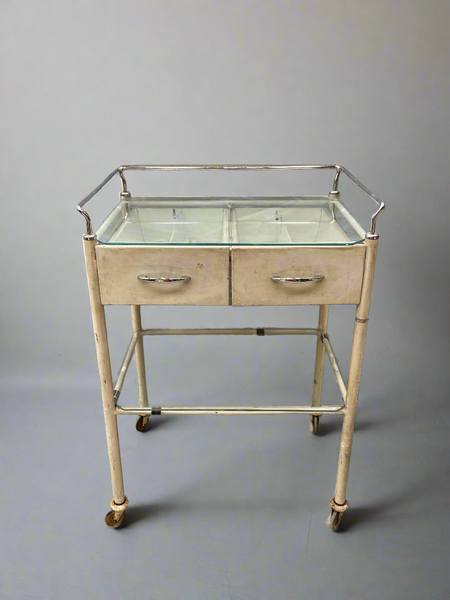 Cream medical trolley with a glass top, on wheels for ease of movement. Ideal hospital ward or dental surgery dressing.