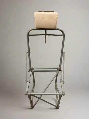 Vintage medical metal chair frame with a padded headrest.