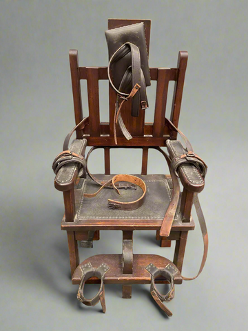 Antique wooden electric chair with leather restraining straps.