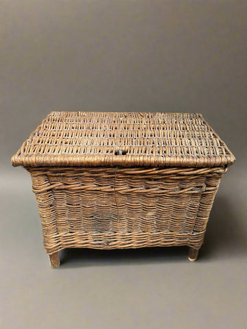 Antique wicker storage hamper on wooden legs, in an aged condition.