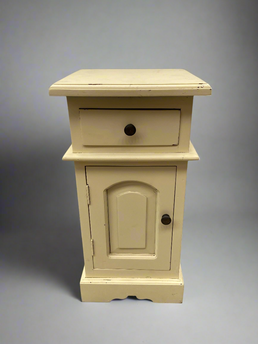 A pair of vintage cream bedside tables, in a rustic country style.