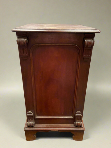 A pair of antique mahogany cabinets with carved scroll detailing.