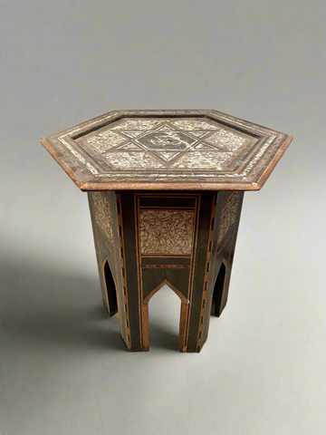 Octagonal six point pedestal table inlaid with mother of pearl marquetry mosaic pieces featuring a central star. The top stands on ebonised timber legs. Likely from Syria or Egypt.