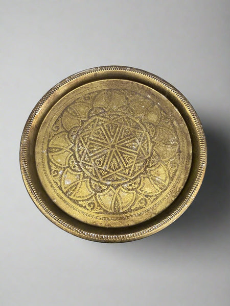 Round brass tea table with an etched ornate symmetrical design.