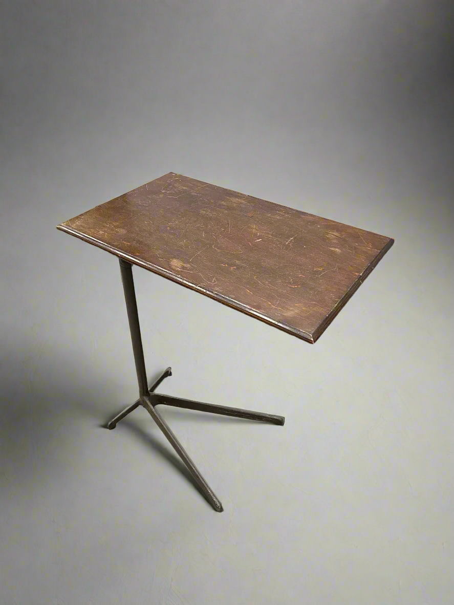 Industrial stand-over-bed table with a wooden top and cast iron legs.