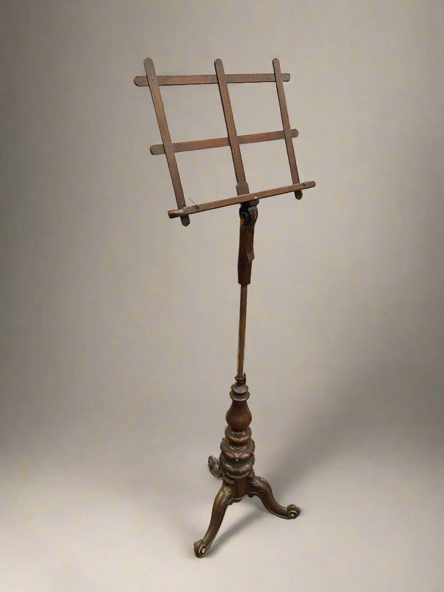 Antique wooden music stand with an ornately carved tripod base.