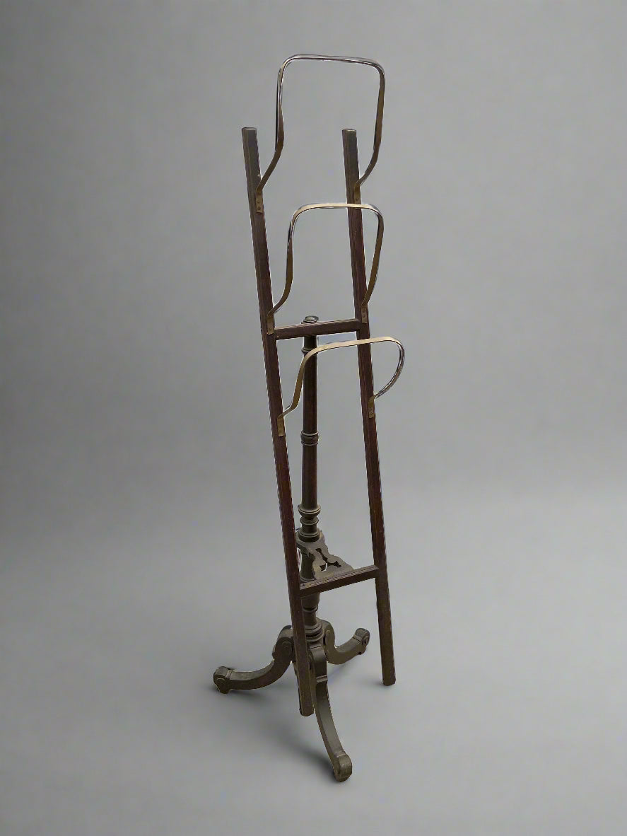 Antique standing magazine rack with three metal tiers and a carved tripod base.