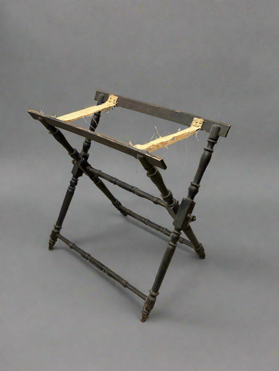 Antique butler's stand with a folding black turned frame and canvas straps.