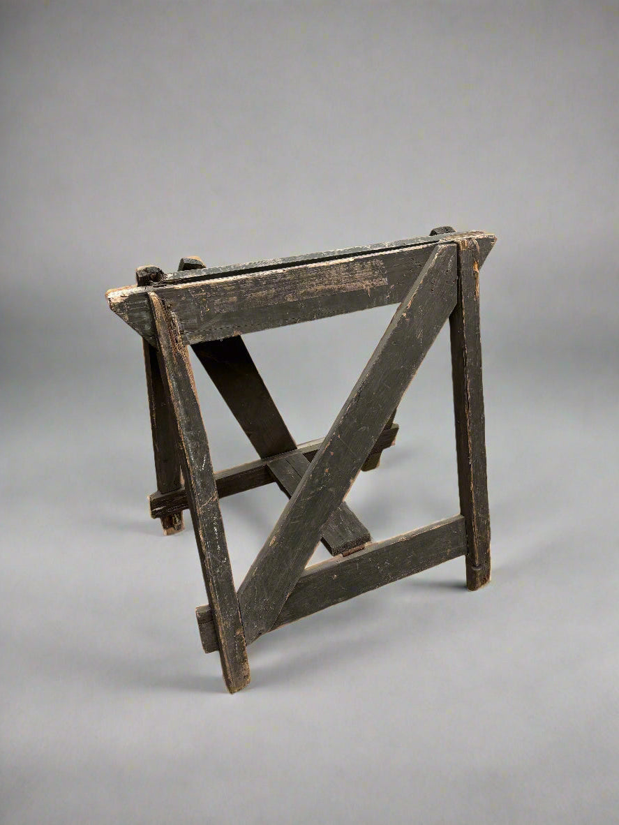 Rustic dark wood trestle stand in an aged condition.