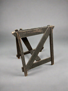 Rustic dark wood trestle stand in an aged condition.