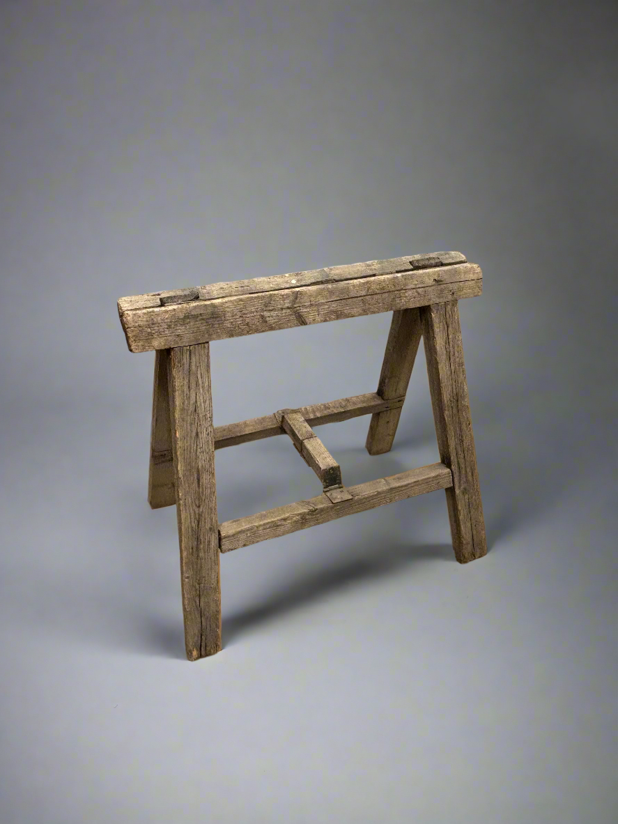 Antique wooden trestle stand with a rustic finish.