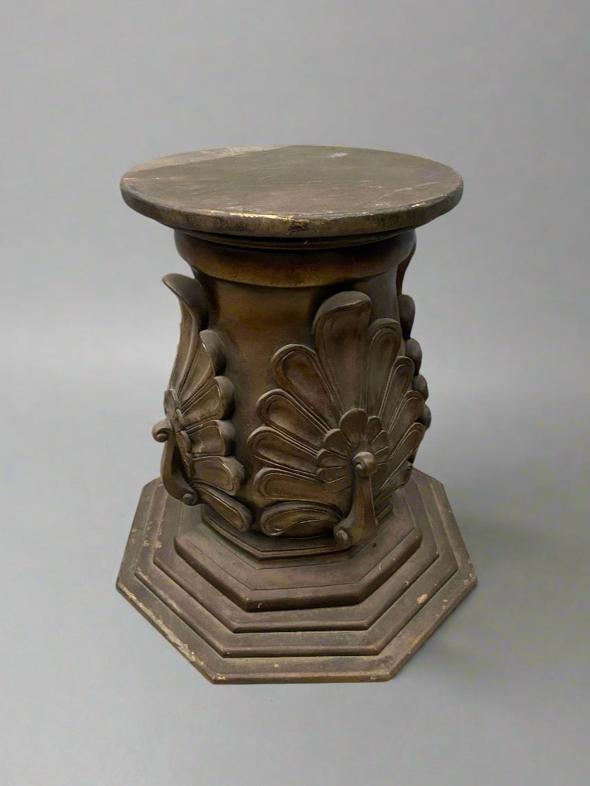 A large bronze pedestal with a peacock plumage design and tiered octagonal base.