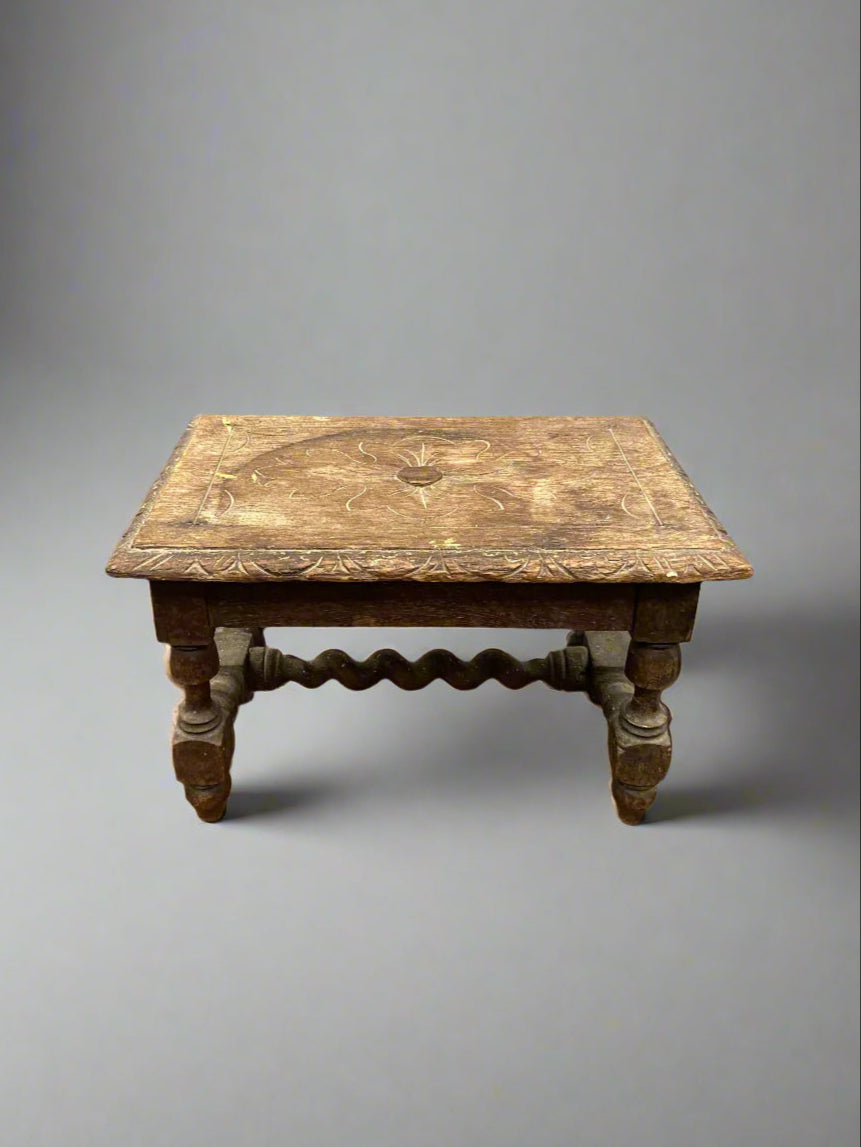 Antique wooden footstool with a floral carved top.