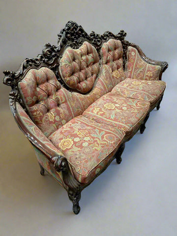 Antique baroque three seater sofa with red and yellow floral upholstery and a buttoned back.